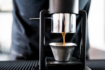 Barista makes an espresso shot on a counter at a cafe