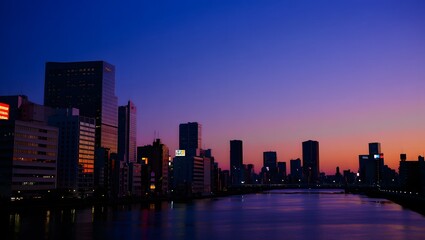 Cityscape silhouette at dusk with river reflection and vibrant sky
