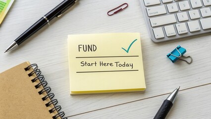 Sticky Note with Fund Message on Desk Surrounded by Office Supplies and Tools for Financial Planning and Productivity