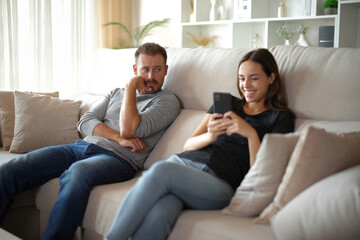 Worried man being ignored by his partner who is chatting online