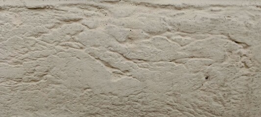 Close up of textured beige wall surface with natural stone like pattern for backgrounds and design elements offering a rustic and organic feel