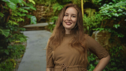 Woman points thumb to green park path lined with dense leafy plants and mossy stones under morning...