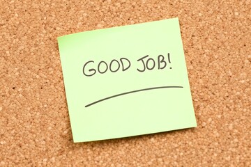 Handwritten message good job on a light green sticky note attached to a corkboard surface