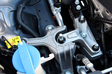 Close-up of vehicles top engine mount showing metal components, bolts, and wiring under hood of...