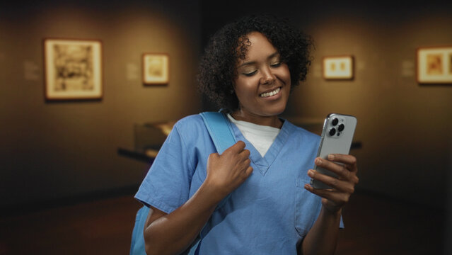 Woman smiling while holding smartphone and backpack strap in building; digital connection joy discovery.