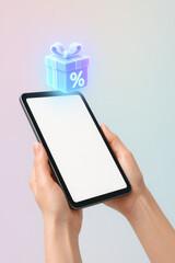 Digital Discount: A person holds a tablet showcasing an illuminated gift box with a percentage symbol, symbolizing special offers and promotions.