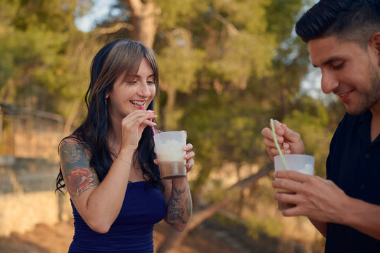 Young couple enjoying iced coffee drinks outdoors