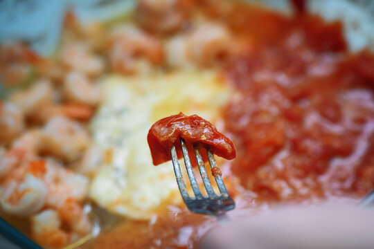 Removing a cherry tomato skin from a fork during sauce preparation for a smooth consistency