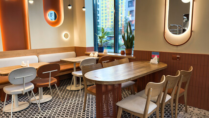 Modern cozy cafe interior with wooden furniture, soft chairs, decorative lighting, large window...