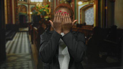 Woman hides face behind hands inside ornate church interior showing red nails and gold hoop...