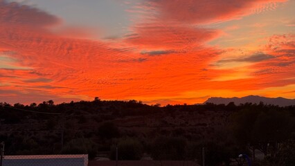 Fiery Sunset Sky: The fiery hues of the setting sun paint the sky in a vibrant display, casting an warm light over the distant horizon.