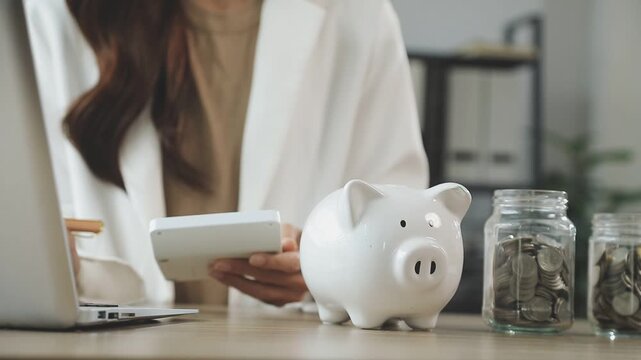 rAsian woman hand put coins in piggy bank,Saving money wealth and financial concept.