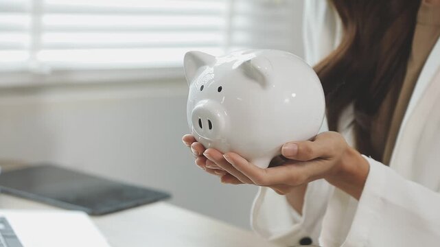 rAsian woman hand put coins in piggy bank,Saving money wealth and financial concept.