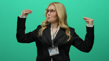 Woman wearing glasses gestures animatedly against a green background in a business suit with id...