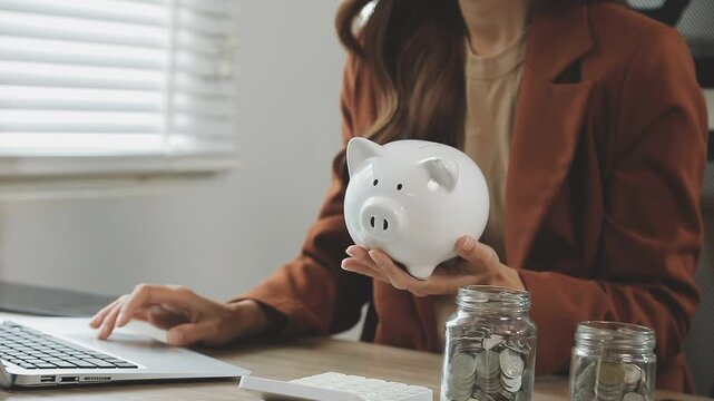 rAsian woman hand put coins in piggy bank,Saving money wealth and financial concept.