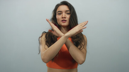 Young woman crosses bare arms in denial gesture in studio under soft lighting with stern...