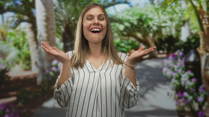 Woman smiling with open palms and bright eyes under warm sunlight and dense trees in forest;...