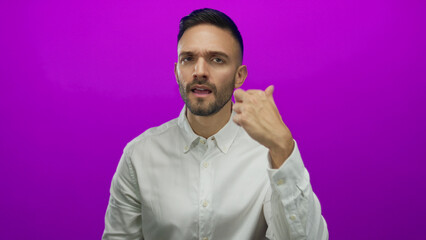 Obraz premium Hispanic man gesturing expressively against vibrant purple background while wearing a white shirt, showing dynamic communication and engaging emotive style.