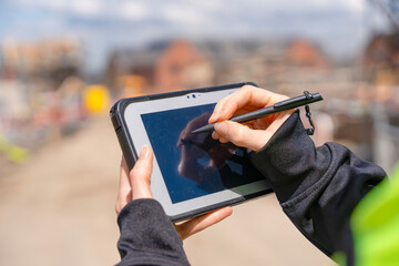 Close-up of woman construction manager useing rugged tablet to record data on construction site