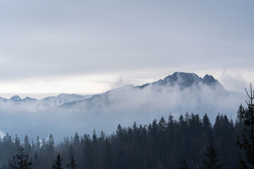 Incredible landscape of snow-capped mountains in clouds and fog