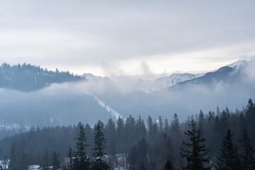 Incredible landscape of snow-capped mountains in clouds and fog