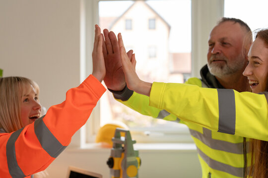 Team of construction professional business people in office giving high five to celebrate success and milestone in the project as a result of teamwork, collaboration and partnership in workplace