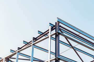 Framework of  modern steel frame building erected against a clear sky during the day showcasing steel construction and architectural design
