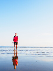 Woman walks along the beach during a summer evening in Sweden surrounded by calm waters and a clear sky
