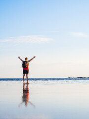 Woman stands on beach in Sweden at summer evening enjoying the sunset over calm waters