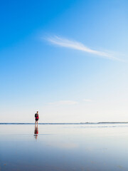 Woman enjoys a peaceful summer evening at the beach in Sweden with calm waters and a clear blue sky
