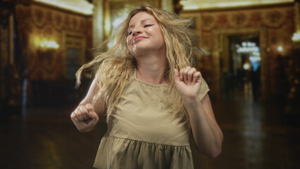 Woman dancing with eyes closed and hands raised in an ornate museum hall lined with chandeliers and gilded columns; joy movement.