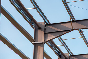 Close-up of steel frame structure elements and connection points against blue sky