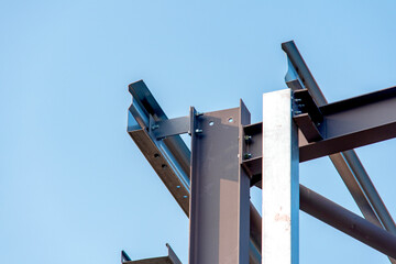 Close-up of steel frame structure elements and connection points against blue sky