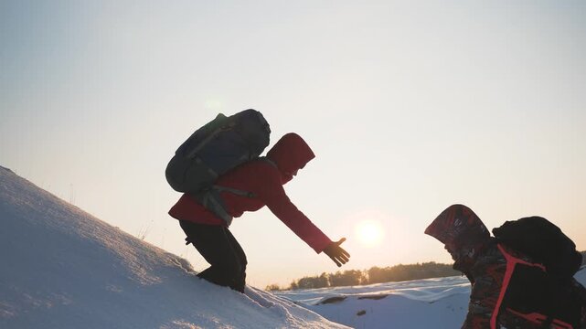 teamwork business. overcome difficulties by giving helping hand fellow partner. two people with backpacks sunset. climber pulls his comrade hand up snowy mountain. go victory. teamwork win. silhouette