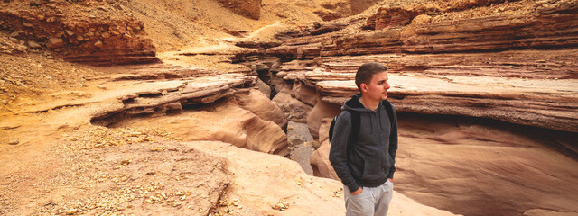 Dry river bed, wilderness. Desert natural landscape. Sandstone texture. Young man walking in Red Canyon in the Negev Desert near Eilat, Israel.