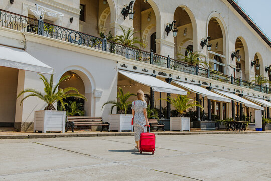 Tourist with suitcase arriving at hotel at sea port on sunny summer day