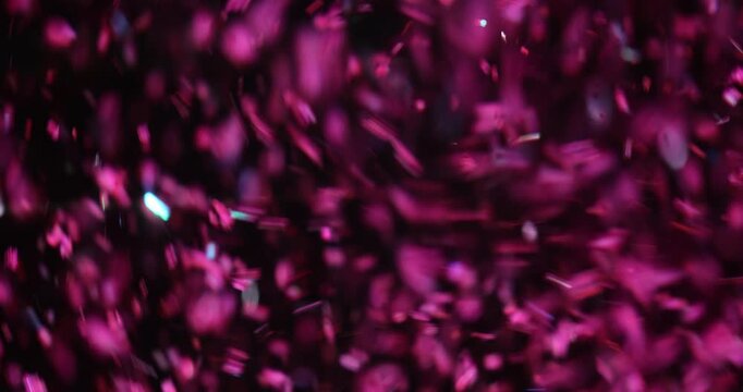 Little pieces of bright pink confetti fly energetically in air. Small fragments of sequins fill atmosphere with vibrant and joyful celebration