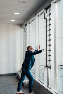 Confident bestager businessman with foresight looking out office window