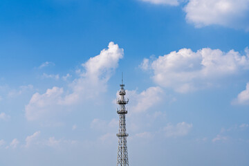 Obraz premium signal transmission tower against the background of blue sky and white clouds