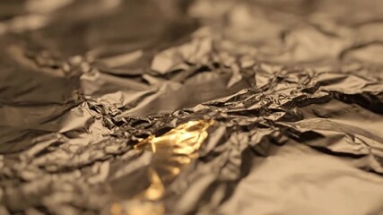 Close-up of crumpled, textured metallic foil in shades of gold and brown, creating a captivating abstract pattern for backgrounds. - Powered by Adobe