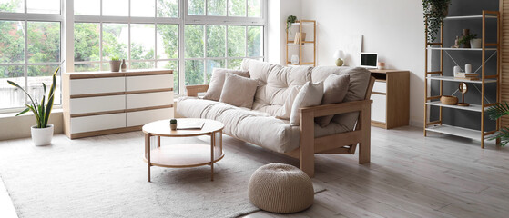 Interior of light living room with beige couch, table and big window