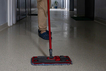 Cleaning the hallway with a mop while wearing comfortable footwear in a well-lit environment