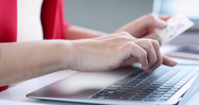 Woman holds bank card typing on laptop for secure online payment. Customer checks total and enters digits confirming purchase during work day