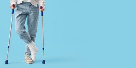 Young woman with broken leg using crutches on light blue background with space for text