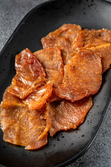Close-up of dried pork jerky on black plate