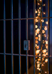 Decorative lights peeking through prison bars at night  