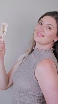 Young woman smiling while holding a portable mini fan, enjoying a cool breeze on a hot summer day.