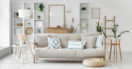 Interior of light living room with beige couch, lamp and plants