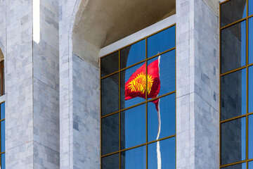 National Flag of Kyrgyzstan reflecting on modern building windows in urban setting