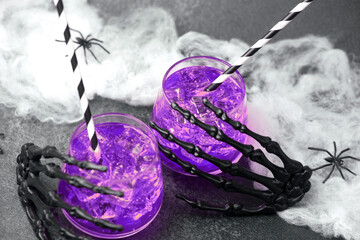 Halloween spooky purple drinks with skeleton hands and spiders on cobwebs